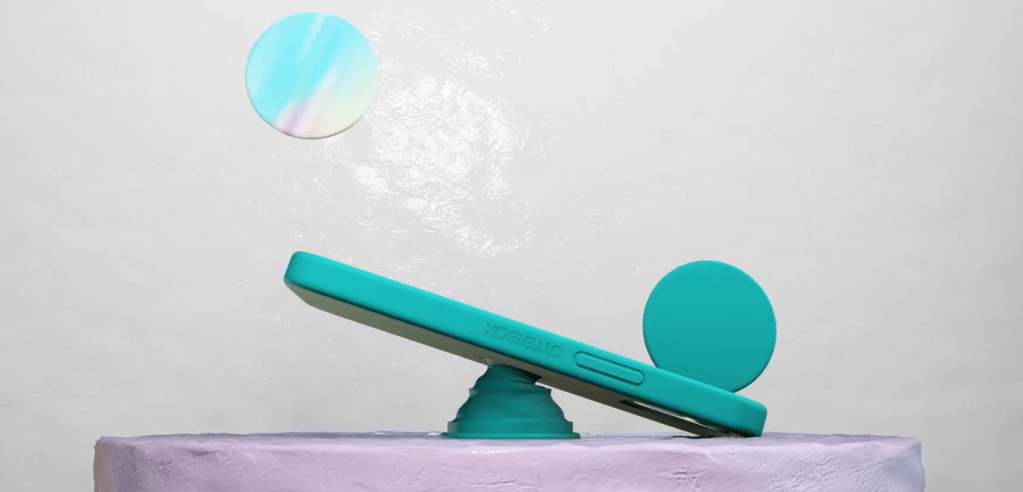 Phone in green teal cases with popsocket balancing on a platform with two other popsockets on either side bouncing